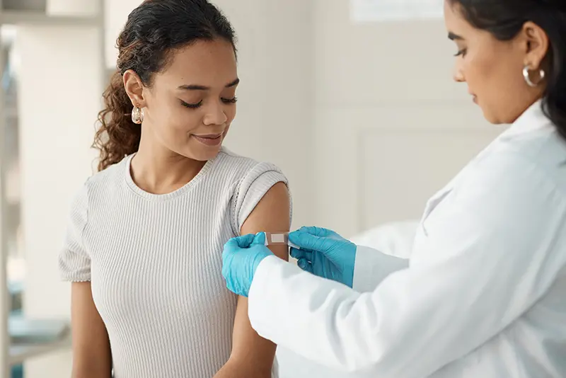 A young doctor applying a band-aid after injecting her patient during a consultation in the clinic