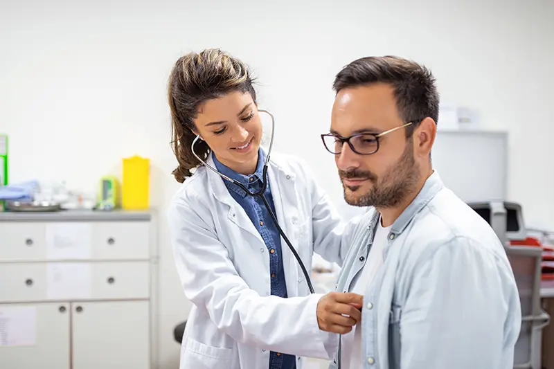 Young doctor using a stethoscope listen to the heartbeat of the patient.